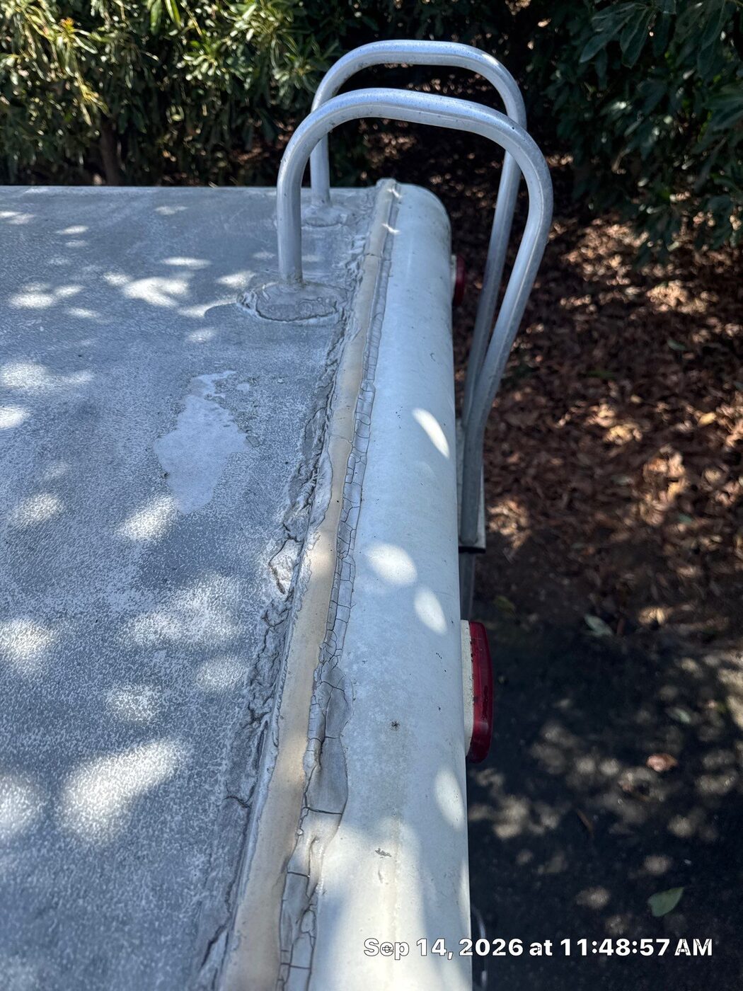 Cracked, weathered lap sealant along the edge rail of an aging EPDM RV roof