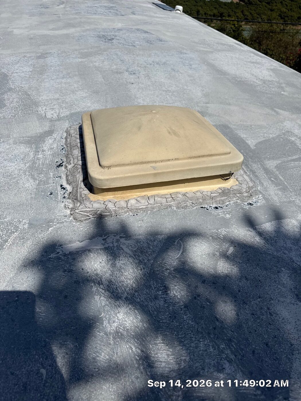Failing, alligatored sealant around a roof vent on an oxidized EPDM RV roof