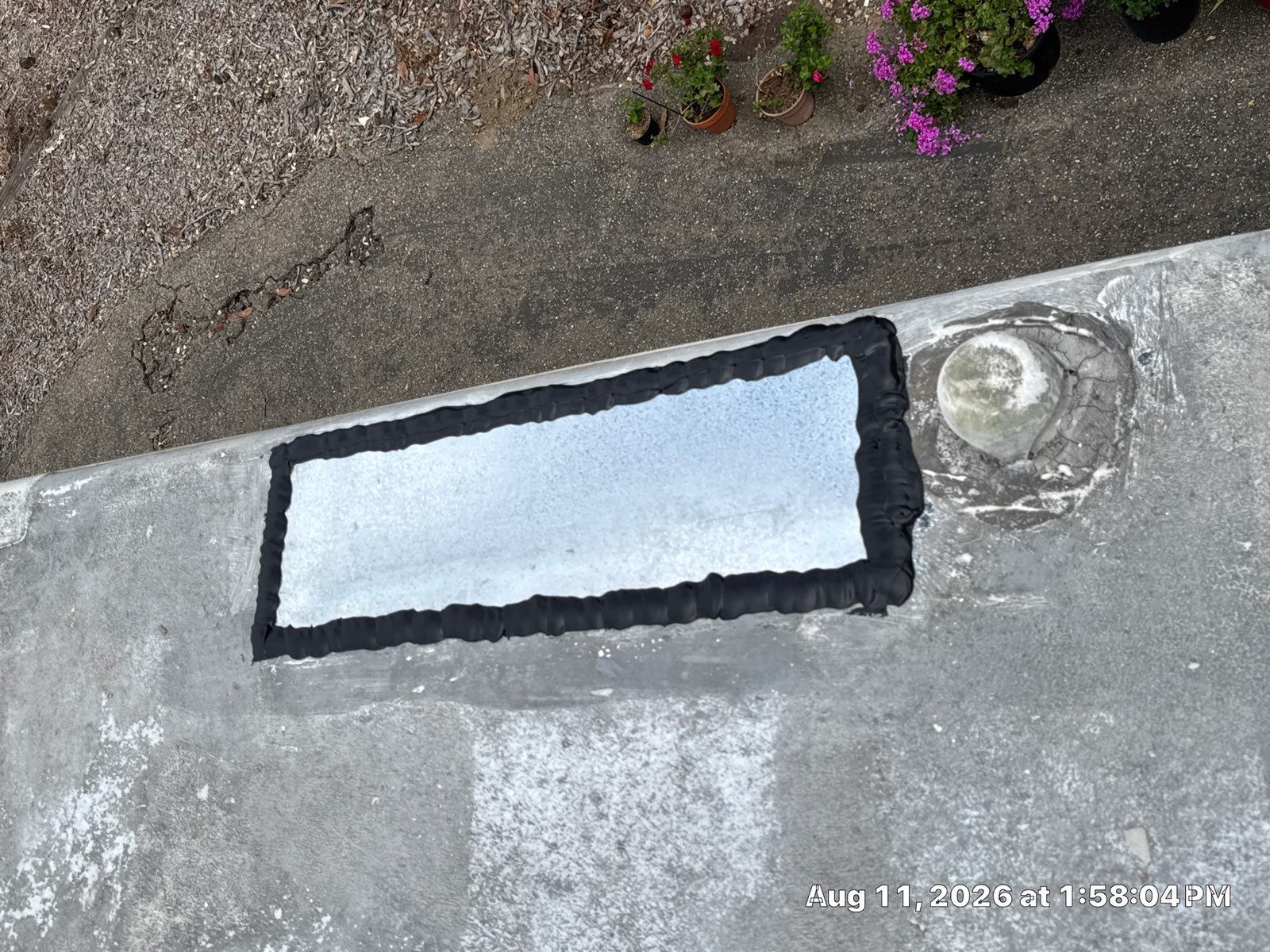 Fresh black self-leveling lap sealant bead around a repaired RV roof patch after resealing