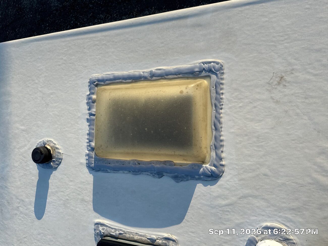 RV skylight reseal with fresh lap sealant next to a plumbing vent