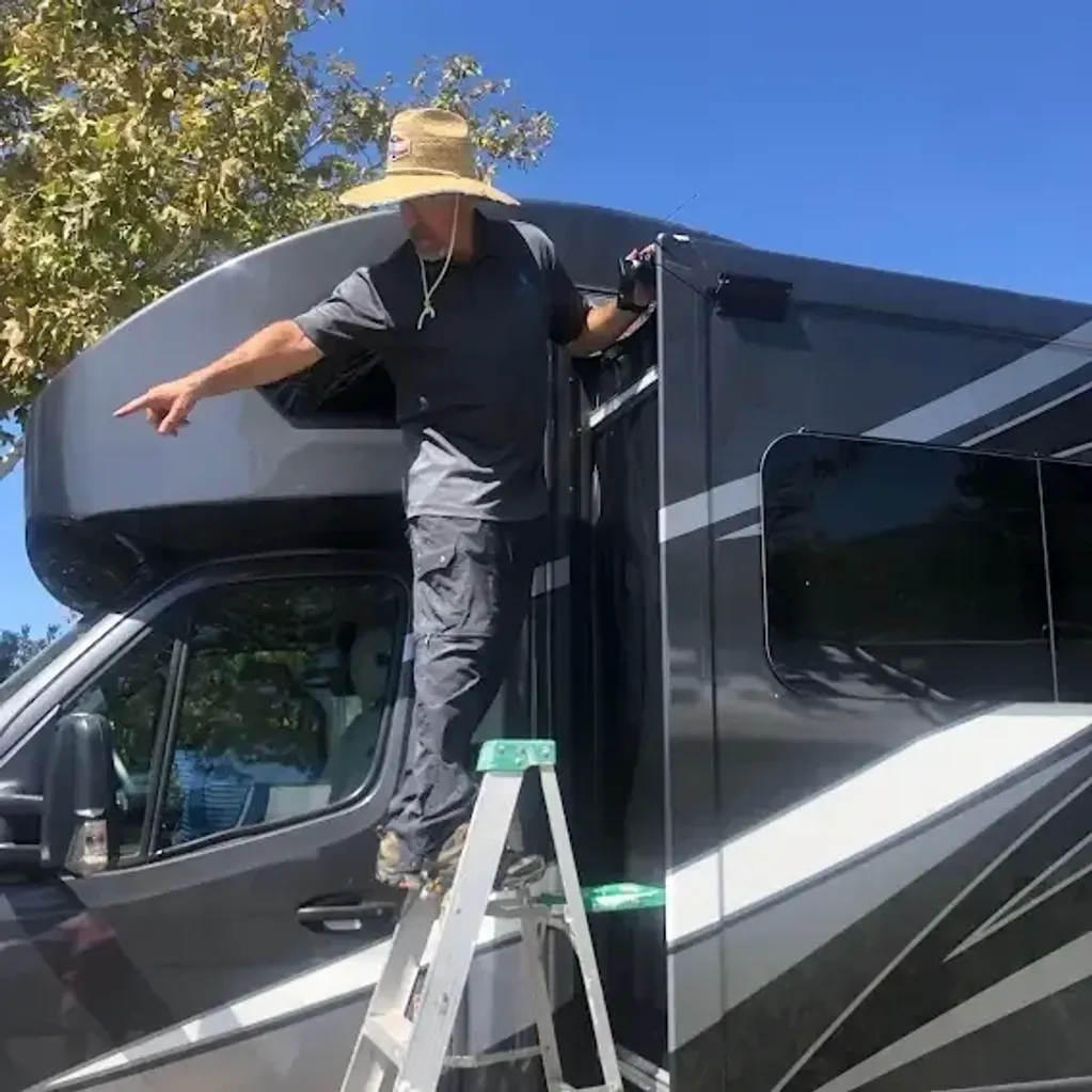 RV slide-out topper repaired on a ladder by Lavender Mobile RV Solutions